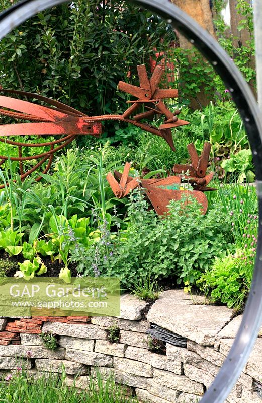 Garten aus recycelten Materialien - Fenster aus Fahrradrädern, Hühnerskulpturen aus alten Mähteilen und mit Gemüse und Kräutern unterpflanzt