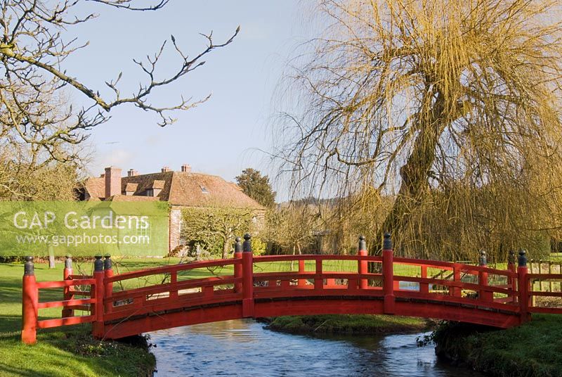 Rote japanische Brücke über den Fluss im Winter, Heale House Gardens, Wiltshire