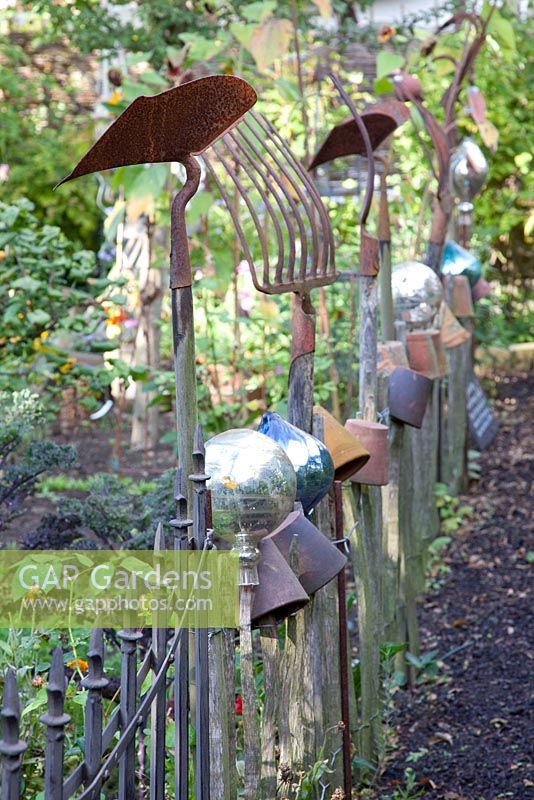 Rustikaler Zaun mit alten Gartengeräten und Geräten