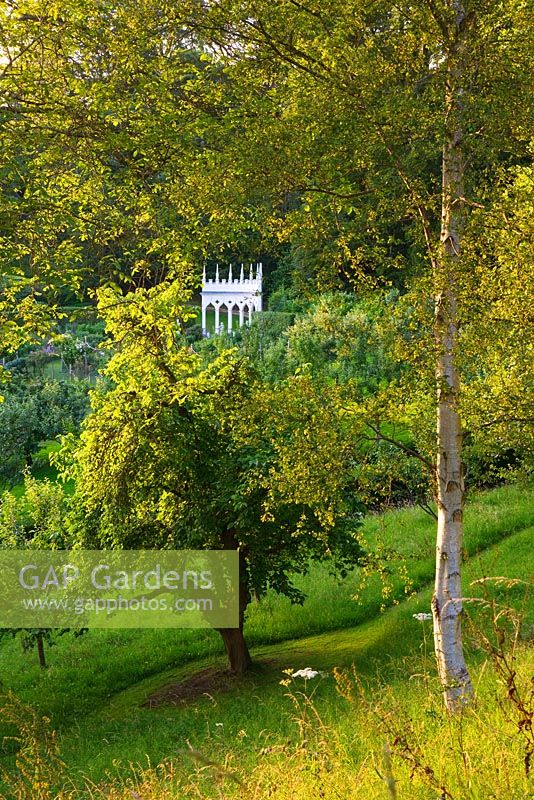 Die Exedra durch Bäume gesehen. Painswick Rococo Garden, Gloucestershire