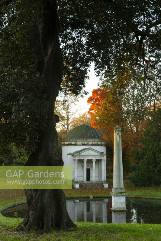 Leuchtendes orangefarbenes Herbstlaub und ein reflektierender Pool neben dem ionischen Tempel und dem Obelisken im Chiswick House and Garden.