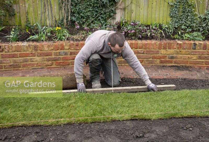 Ein Arbeiter, der während der Renovierung eines Londoner Gartens neuen Rasen verlegt.