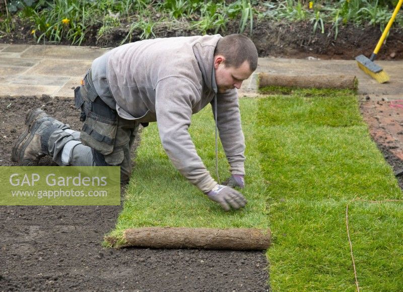 Ein Arbeiter, der während der Renovierung eines Londoner Gartens neuen Rasen verlegt.