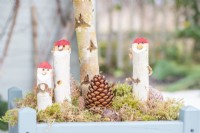 Birkenstock Weihnachtsmänner stehen im Moos am Fuß eines Baumes