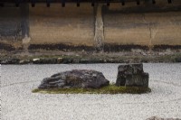 Der Steingarten mit geharktem Kies und platzierten Steinen auf einer Moosinsel. Wände aus Lehm. 