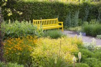 Bank im gelb gestalteten Garten mit Spiraea japonica Golden Princess 
